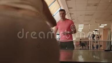 英俊的运动男子正在现代健身房与无名女子打乒乓球或乒乓球。 4K录像。